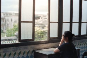 young woman thinking alone cafe window