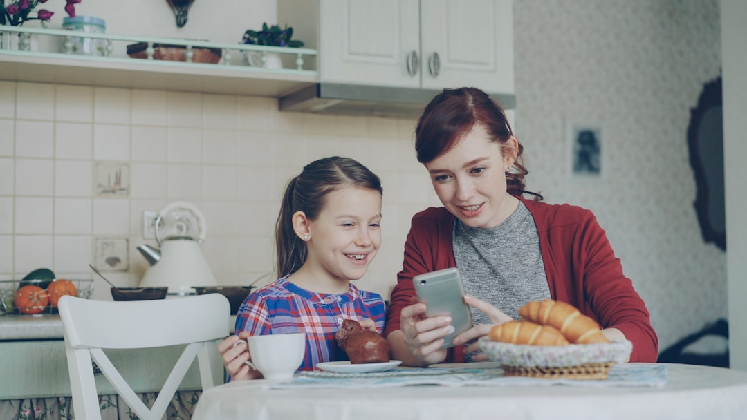 single mother smiling smartphone bright kitchen