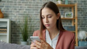 woman typing message on smartphone at home