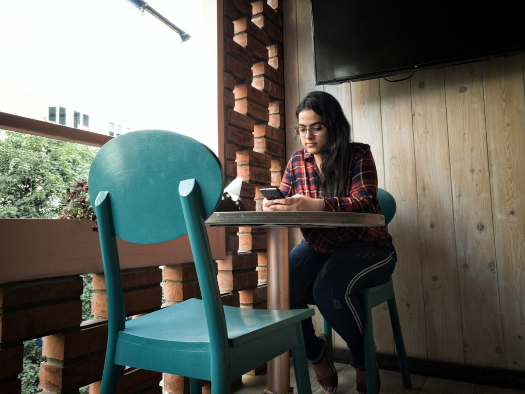 young woman sitting alone in cafe with smartphone