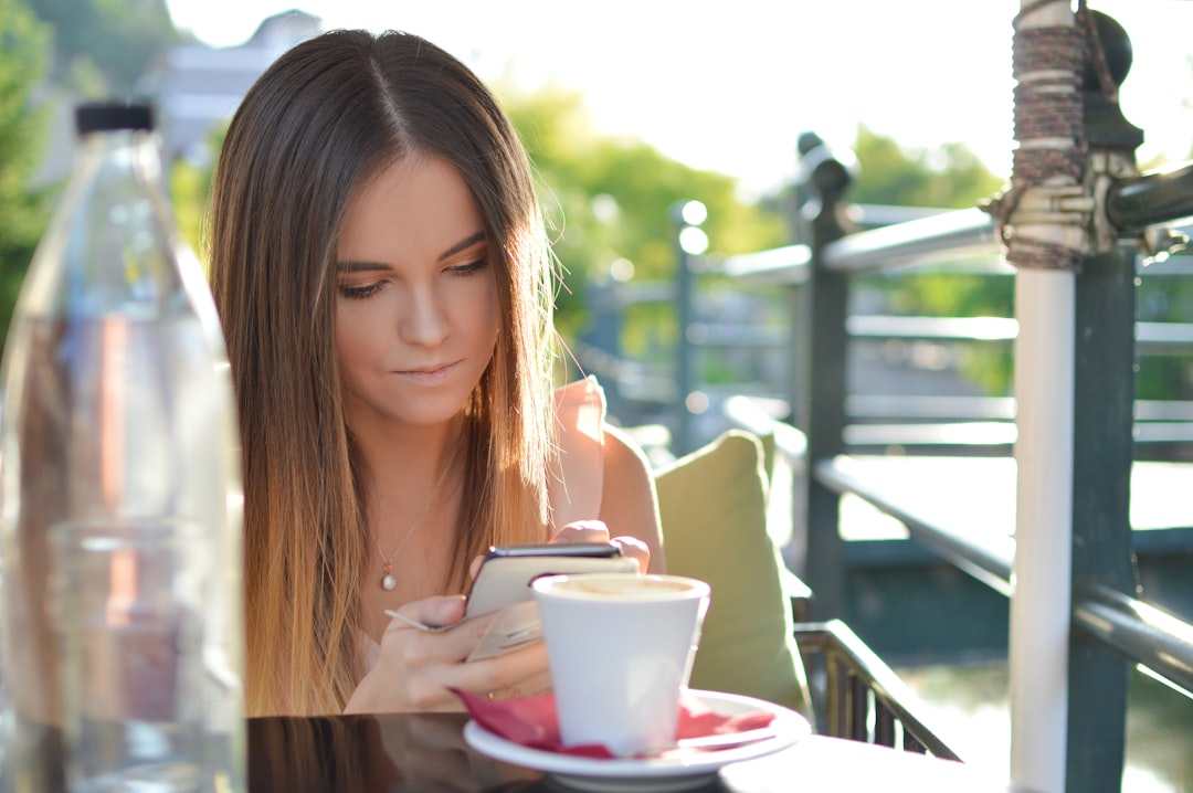 young woman checking smartphone statistics coffee
