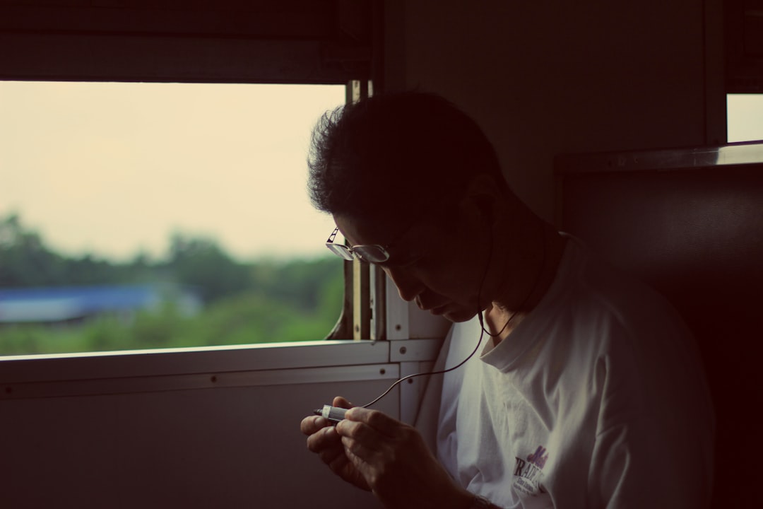 man frowning at smartphone in evening train