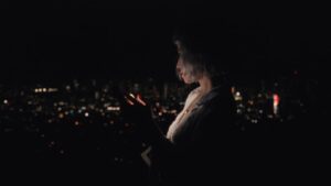 woman thinking with smartphone at night