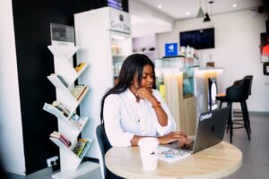 woman thinking laptop cafe decision
