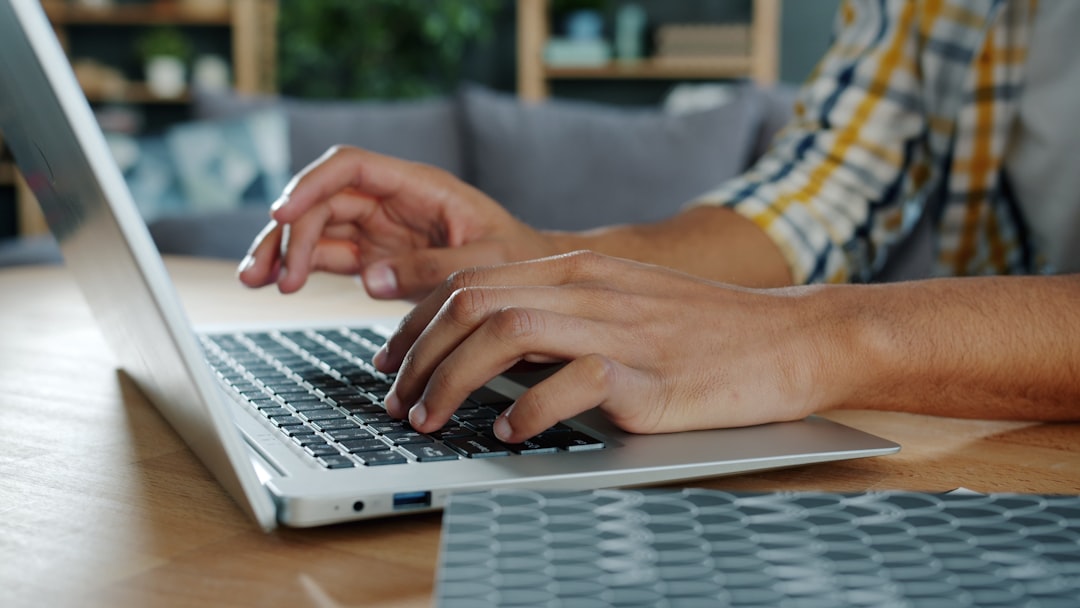 man writing on laptop at home desk