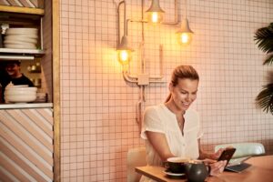 woman comparing two smartphones cafe
