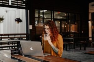 woman thinking with laptop cafe