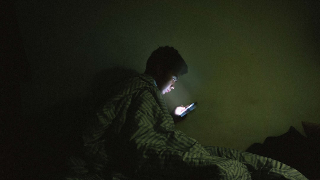 young man worried smartphone bed night