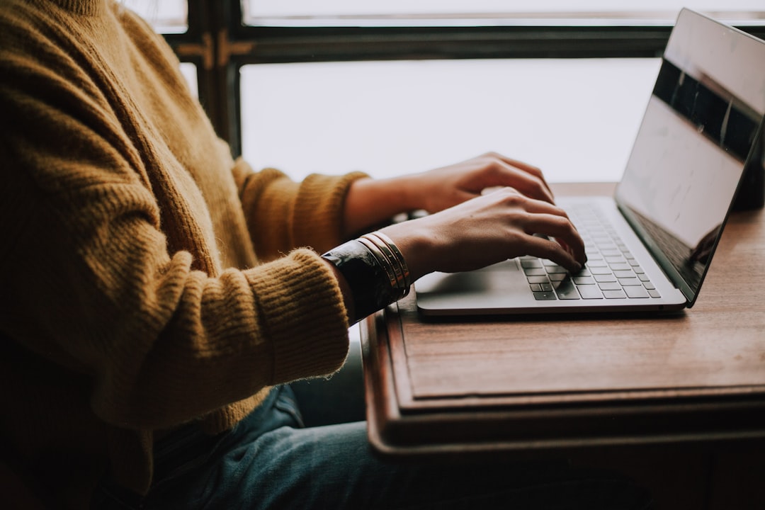 person typing profile on laptop cozy room