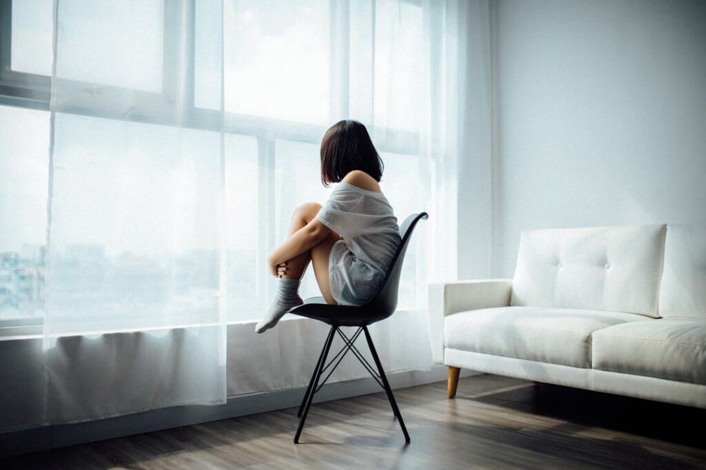 young woman thinking alone by window