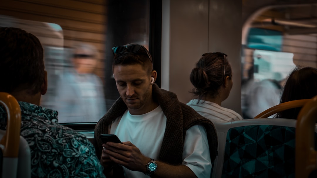 man frowning at smartphone evening train