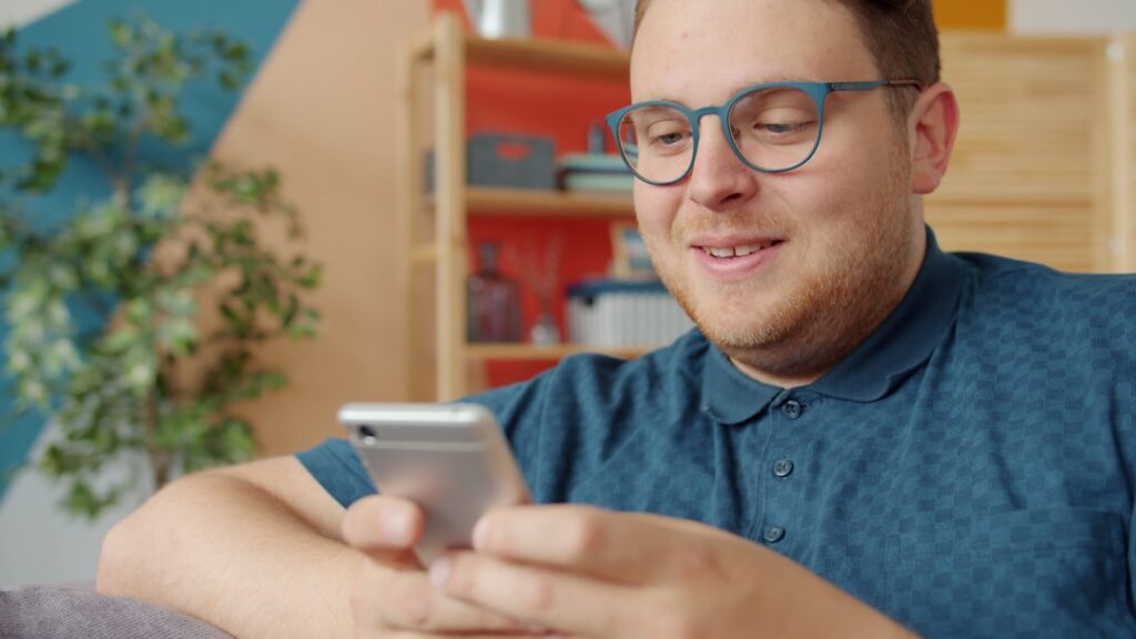 man typing message on smartphone smiling