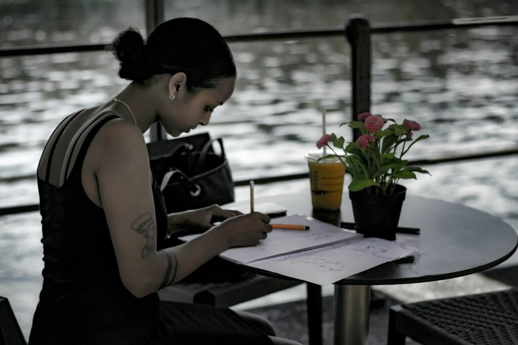 woman writing notebook cafe thinking smartphone