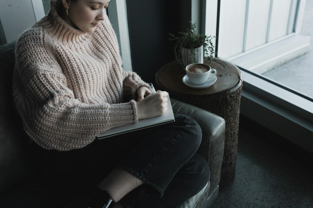 woman writing notebook cafe thinking