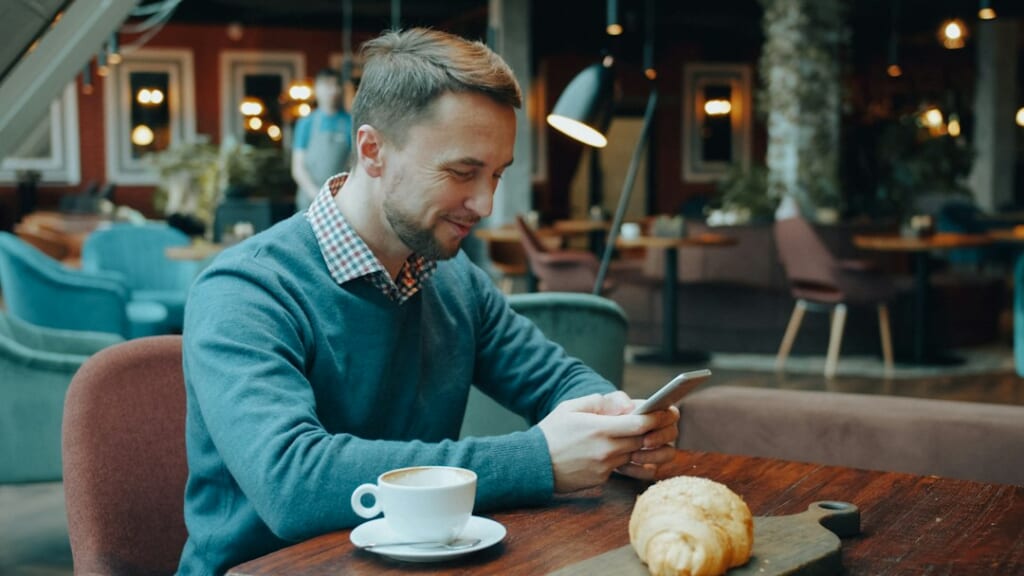 person texting on smartphone cafe