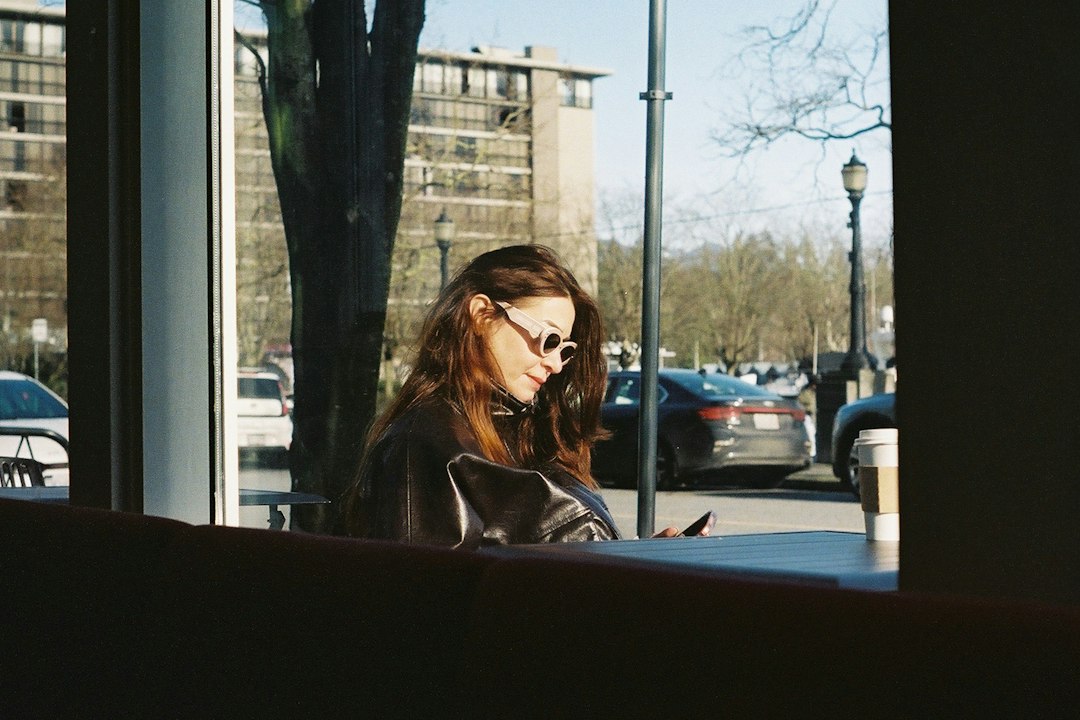 woman browsing phone cafe window